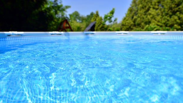 Swimming pool with metal frame for home and garden. Frame swimming pool in the yard. Garden in the background. Summer holiday fun and recreation. photo
