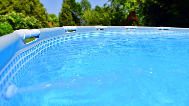 Swimming pool with metal frame for home and garden. Frame swimming pool in the yard. Garden in the background. Summer holiday fun and recreation. photo