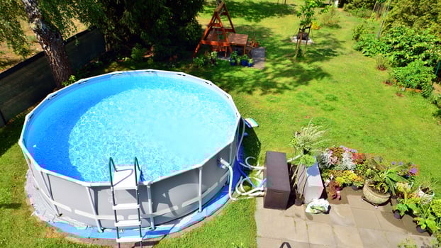 Swimming pool with metal frame for home and garden. Frame swimming pool in the yard. Garden in the background. Summer holiday fun and recreation. photo