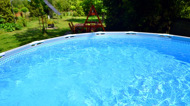 Swimming pool with metal frame for home and garden. Frame swimming pool in the yard. Garden in the background. Summer holiday fun and recreation. photo