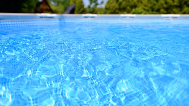 Swimming pool with metal frame for home and garden. Frame swimming pool in the yard. Garden in the background. Summer holiday fun and recreation. photo