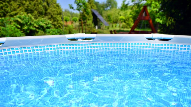 Swimming pool with metal frame for home and garden. Frame swimming pool in the yard. Garden in the background. Summer holiday fun and recreation. photo