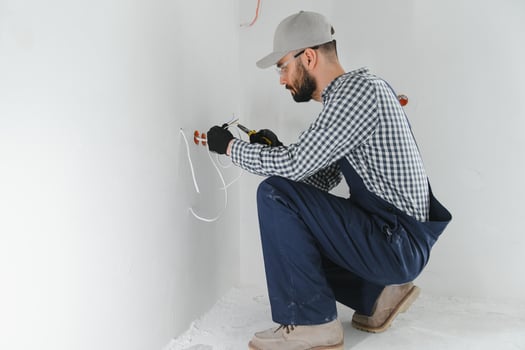 electrician installs socket boxes on the wall and puts a putty on them photo