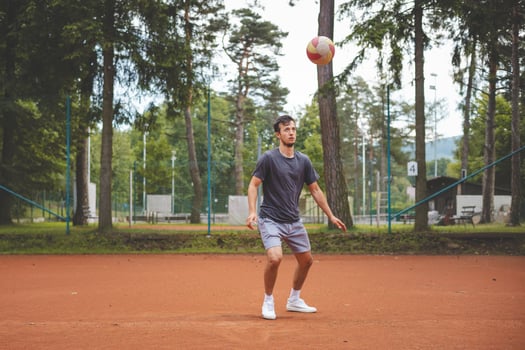 Soccer player in 20s plays with a balloon on a clay court. Amateur sport. Individual football training. Soccer. Kicking, striking, passing and dribbling photo