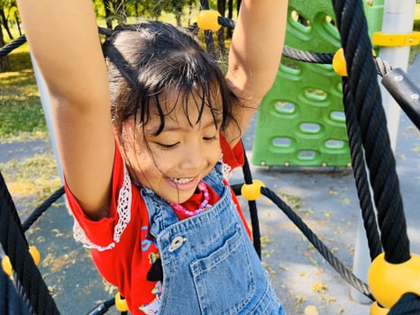Cute Asian preschooler girl having fun on outdoor playground. Spring summer autumn active sport leisure for child. Activity for family with children. Equipment of entertainment park for kids. photo