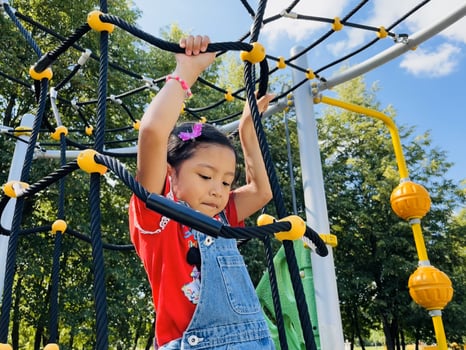 Cute Asian preschooler girl having fun on outdoor playground. Spring summer autumn active sport leisure for child. Activity for family with children. Equipment of entertainment park for kids. photo