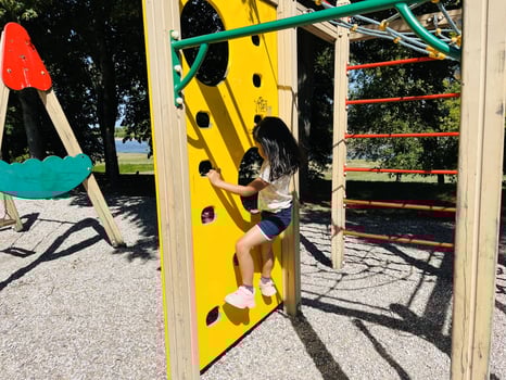 Cute Asian preschooler girl having fun on outdoor playground. Spring summer autumn active sport leisure for child. Activity for family with children. Equipment of entertainment park for kids. photo