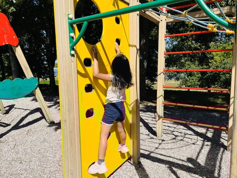 Cute Asian preschooler girl having fun on outdoor playground. Spring summer autumn active sport leisure for child. Activity for family with children. Equipment of entertainment park for kids. photo
