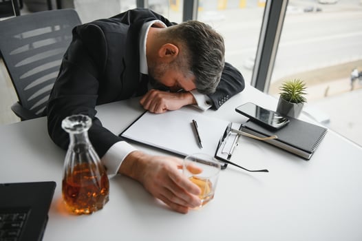 Old business man is drinking alchool at the office photo