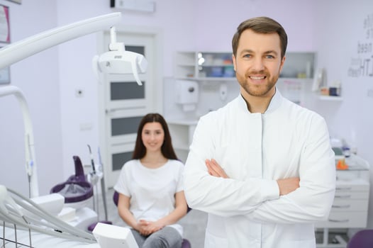 Male dentist in a room with medical equipment and patient on background. photo