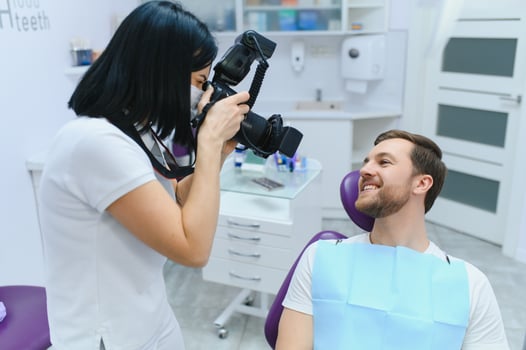 Handsome man smiling while teeth exam. Happy male patient sitting in a dentist's chair and having check up teeth. photo
