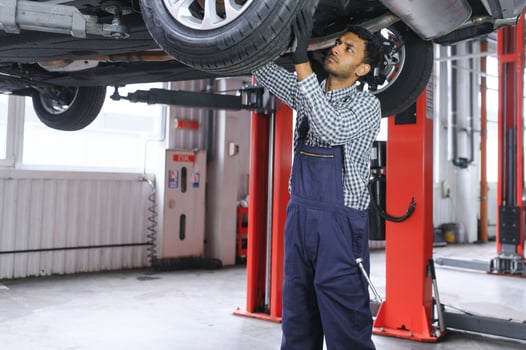 latin hispanic auto mechanic in uniform is examining a car while working in auto service photo