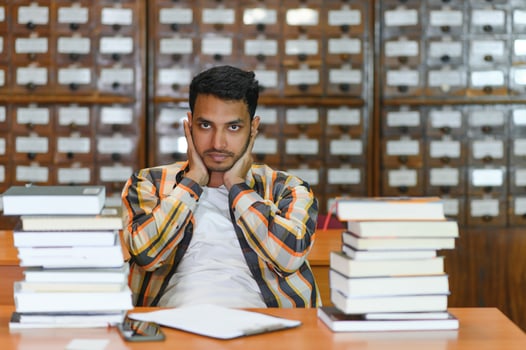 Male indian student at the library with book photo