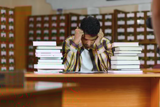 Clever arabian or indian male student or freelancer, in stylish casual clothes in the library photo