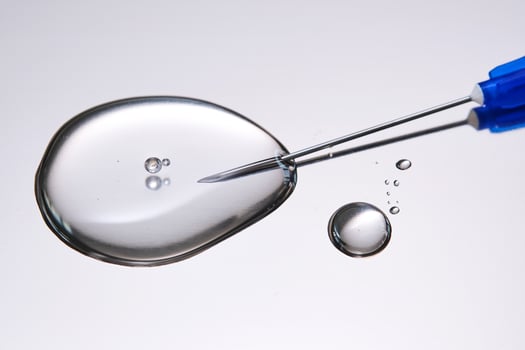 A drop of medicine flowing from a syringe with a needle. photo