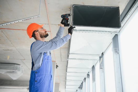 Industrial Theme. Warehouse Heating and Cooling System Installation by Professional Caucasian Technician. Commercial Building Ventilation Rectangle Canals. Air Distribution. photo