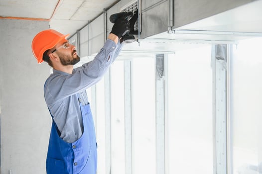 Industrial Theme. Warehouse Heating and Cooling System Installation by Professional Caucasian Technician. Commercial Building Ventilation Rectangle Canals. Air Distribution. photo