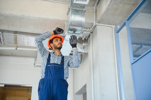 hvac services - indian worker install ducted pipe system for ventilation and air conditioning in house photo