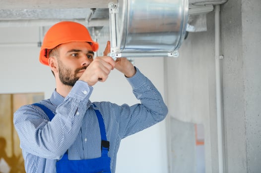 hvac worker install ducted pipe system for ventilation and air conditioning. copy space photo