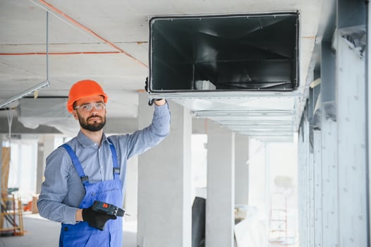 Industrial Theme. Warehouse Heating and Cooling System Installation by Professional Caucasian Technician. Commercial Building Ventilation Rectangle Canals. Air Distribution. photo