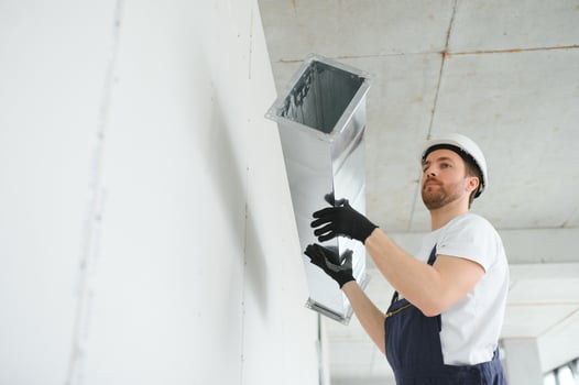 Professional HVAC Worker on a Aluminium Scaffolding Installing Air Duct Inside Newly Built Commercial Building. Industrial Theme photo