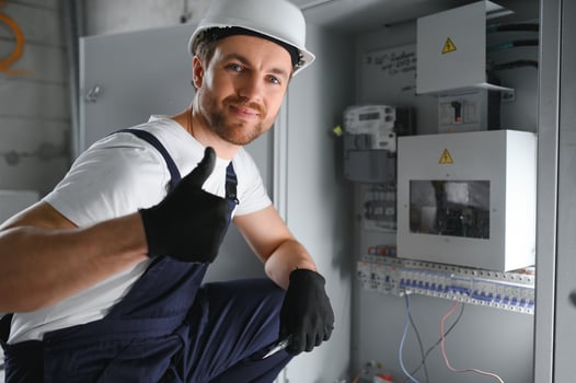 Man, an electrical technician working in a switchboard with fuses. Installation and connection of electrical equipment. Professional with tools in hand. concept of complex work, space for text. photo