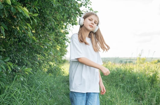 A child with headphones listening to music and dancing in the park. photo