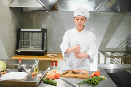 Portrait of young beautiful female chef in restaurant kitchen photo