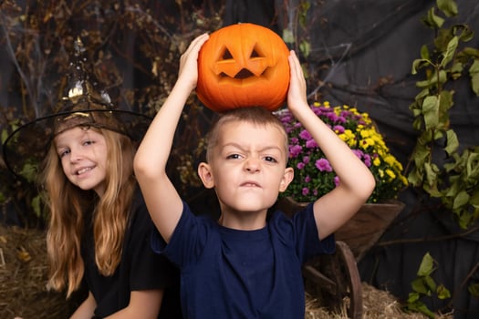close-up portrait of happy, funny boy and a girl playing with pumpkin. children playing and preparation for halloween photo