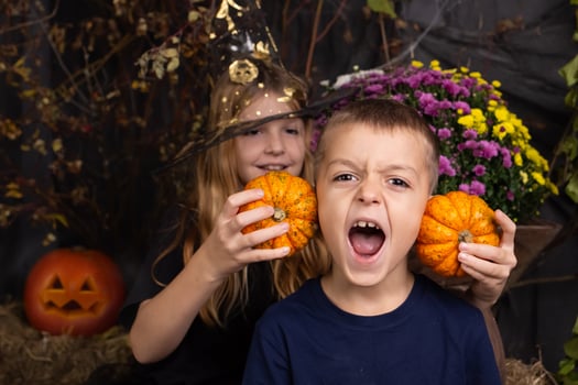 close-up portrait of happy, funny boy and a girl playing with pumpkin. children playing and preparation for halloween photo