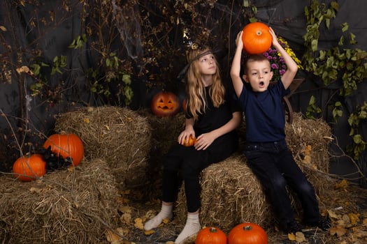 Happy brother and sister on Halloween. Funny children in carnival costumes indoors. Cheerful children play with pumpkins photo