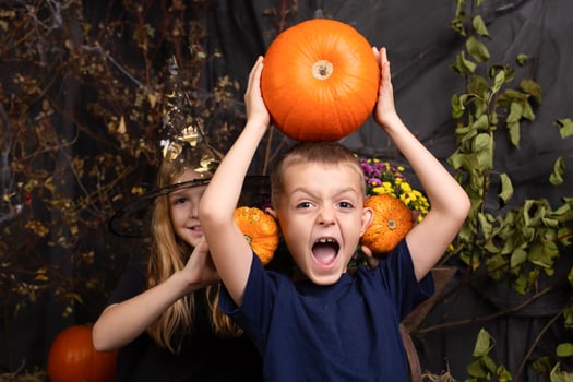 close-up portrait of happy, funny boy and a girl playing with pumpkin. children playing and preparation for halloween photo