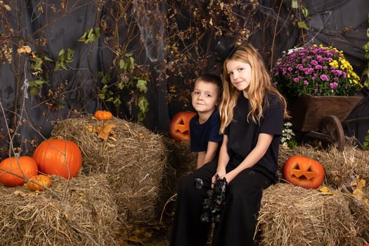 Happy brother and sister on Halloween. Funny children in carnival costumes indoors. Cheerful children play with pumpkins photo
