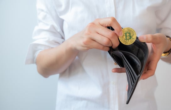 Cropped shot of woman collecting golden Bitcoin token in leather wallet. Bitcoin is one of the popular cryptocurrency, a virtual currency or a digital currency. photo