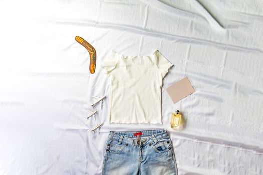 On the table were models card, perfumes and notebooks lying around a white shirt and jeans. photo