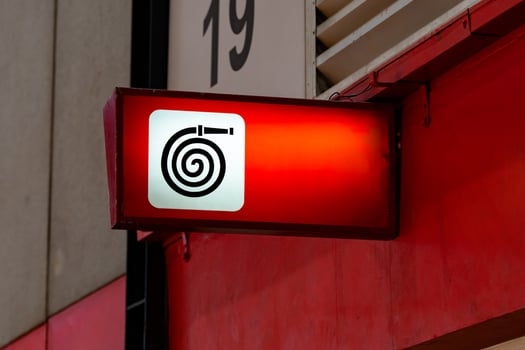 A fire equipment sign installed on a wall. Red light on to be noticeable in an exhibition hall that contains many participants. photo