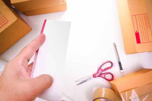 Blank white bill in a hand with goods boxes for packing , goods delivery concept , top view photo