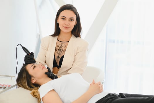 Cosmetologist applying permanent make up on eyebrows- eyebrow tattoo photo