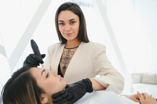 Cosmetologist applying permanent make up on eyebrows- eyebrow tattoo photo