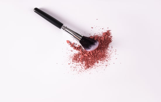 A sample of pink loose blush on a white background with a makeup brush. A copy space. top view. a layout for advertising the product. photo