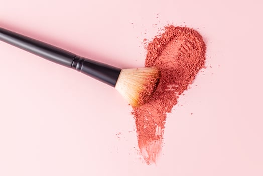 An elegant makeup brush rests on a loose blush swatch with a universal tone. pastel background. A copy space. View from above. Layout, product design. photo