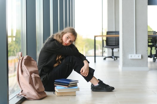 Lonely sad schoolgirl while all her classmates ignored her. Social exclusion problem. Bullying at school concept. photo