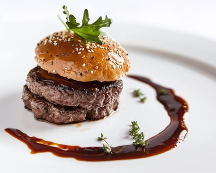 a hamburger with sauce and garnish on a white plate photo