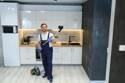 Happy Male Janitor Cleaning Carpet With Vacuum Cleaner photo