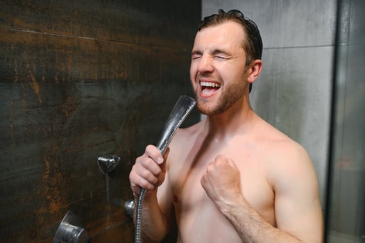 Handsome man singing while taking shower at home photo
