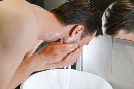 A man washes his face after shaving photo