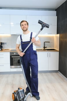 Happy Male Janitor Cleaning Carpet With Vacuum Cleaner photo