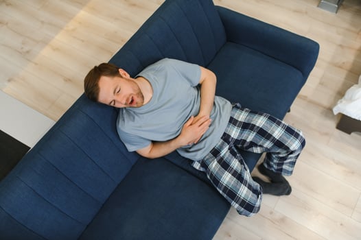 Young man suffering from stomach ache at home photo