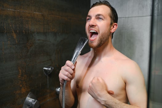 Handsome man singing while taking shower at home photo