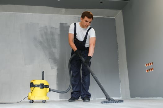 male worker in overall vacuum cleaning during apartment renovation photo